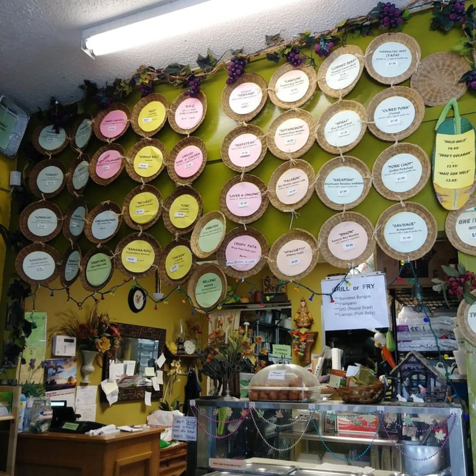 A wall of Lutong Bahay's menu items, each on a small woven plate, above a counter.