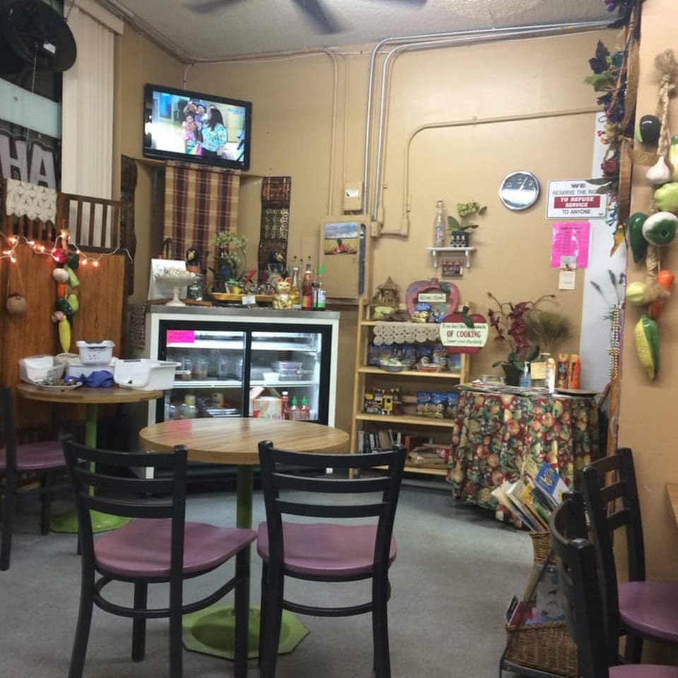 Interior of Lutong Bahay, a Filipino restaurant, with tables, chairs, a TV, and shelves of items.