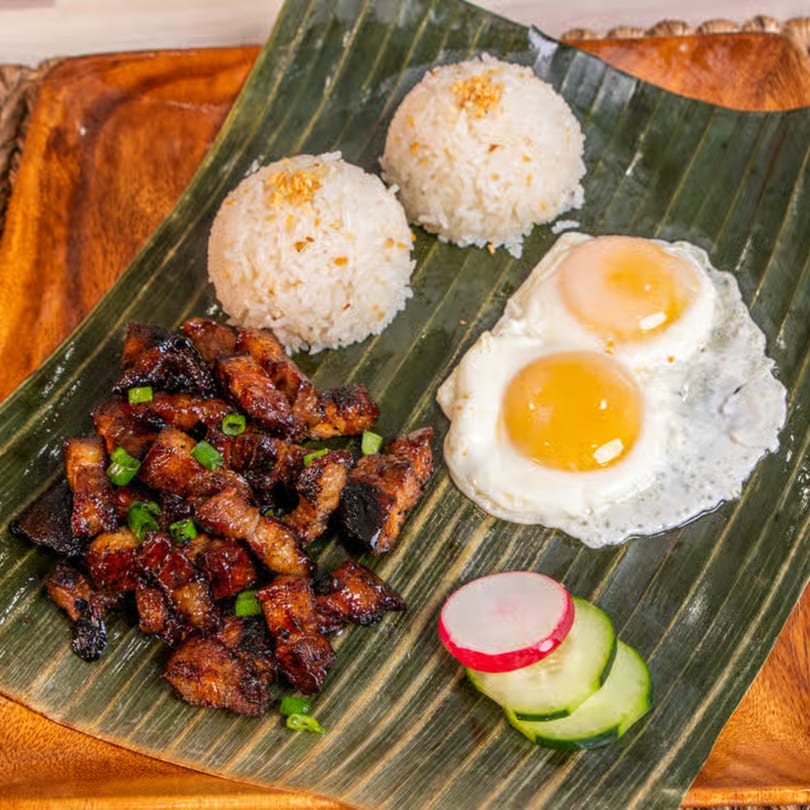 Filipino Lutong Bahay silog meal with pork belly, two fried eggs, garlic rice, and sliced radish.